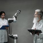 Dois pesquisadores trabalham com um braço robótico em um laboratório, representando pesquisa, inovação e desenvolvimento tecnológico.