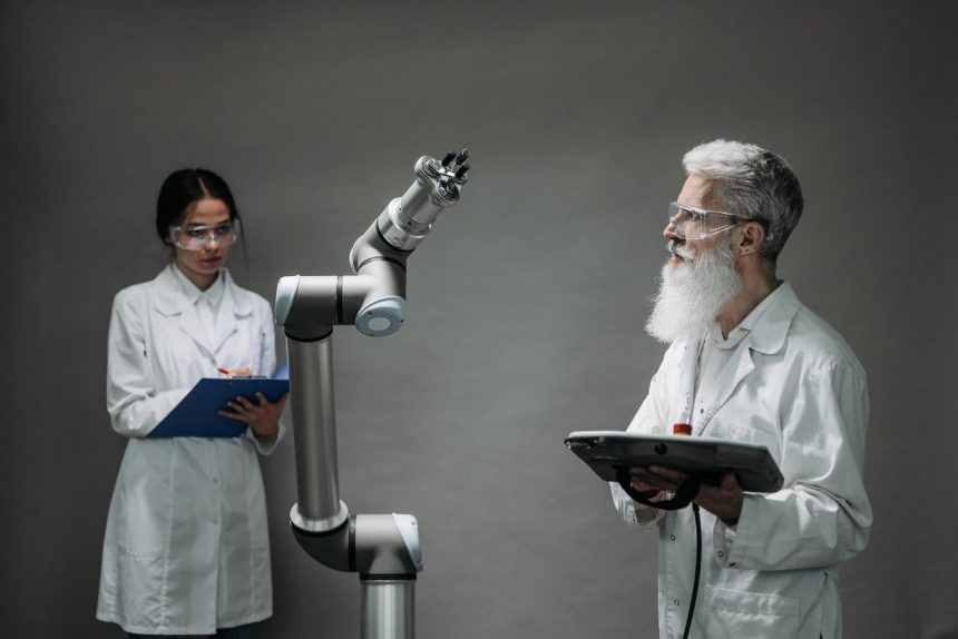 Dois pesquisadores trabalham com um braço robótico em um laboratório, representando pesquisa, inovação e desenvolvimento tecnológico.