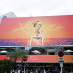Grande painel publicitário com imagens vibrantes em Cannes, em contexto de evento audiovisual.