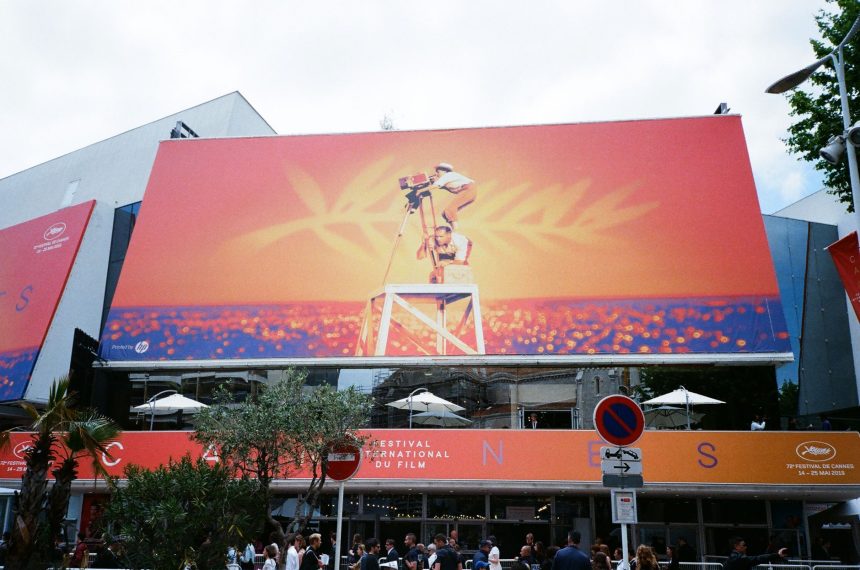 Grande painel publicitário com imagens vibrantes em Cannes, em contexto de evento audiovisual.