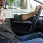 Motorista ao volante de um carro com documento de habilitação desfocado nas mãos