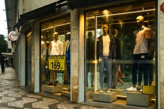 Interior de uma loja de moda masculina em São Paulo, com manequins e roupas expostas na vitrine.