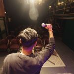 Creator segura um microfone no palco e se prepara para uma apresentação diante de um auditório.