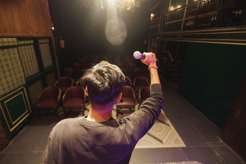 Creator segura um microfone no palco e se prepara para uma apresentação diante de um auditório.