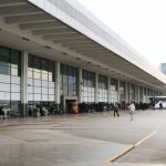 Vista ampla de um terminal rodoviário movimentado, com passageiros e ônibus estacionados.