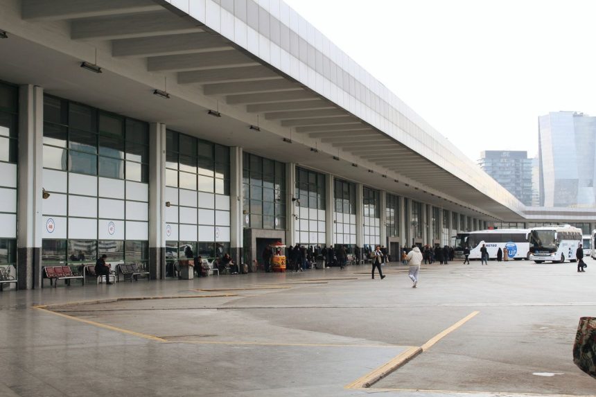 Vista ampla de um terminal rodoviário movimentado, com passageiros e ônibus estacionados.